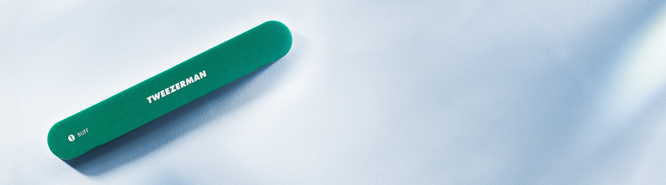 Green nail file with 'Tweezerman' branding on a light blue background