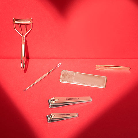 Red background with heart shadow, rose gold eyelash curler, nonslip blackhead remover, mini slant with case and combo clipper set