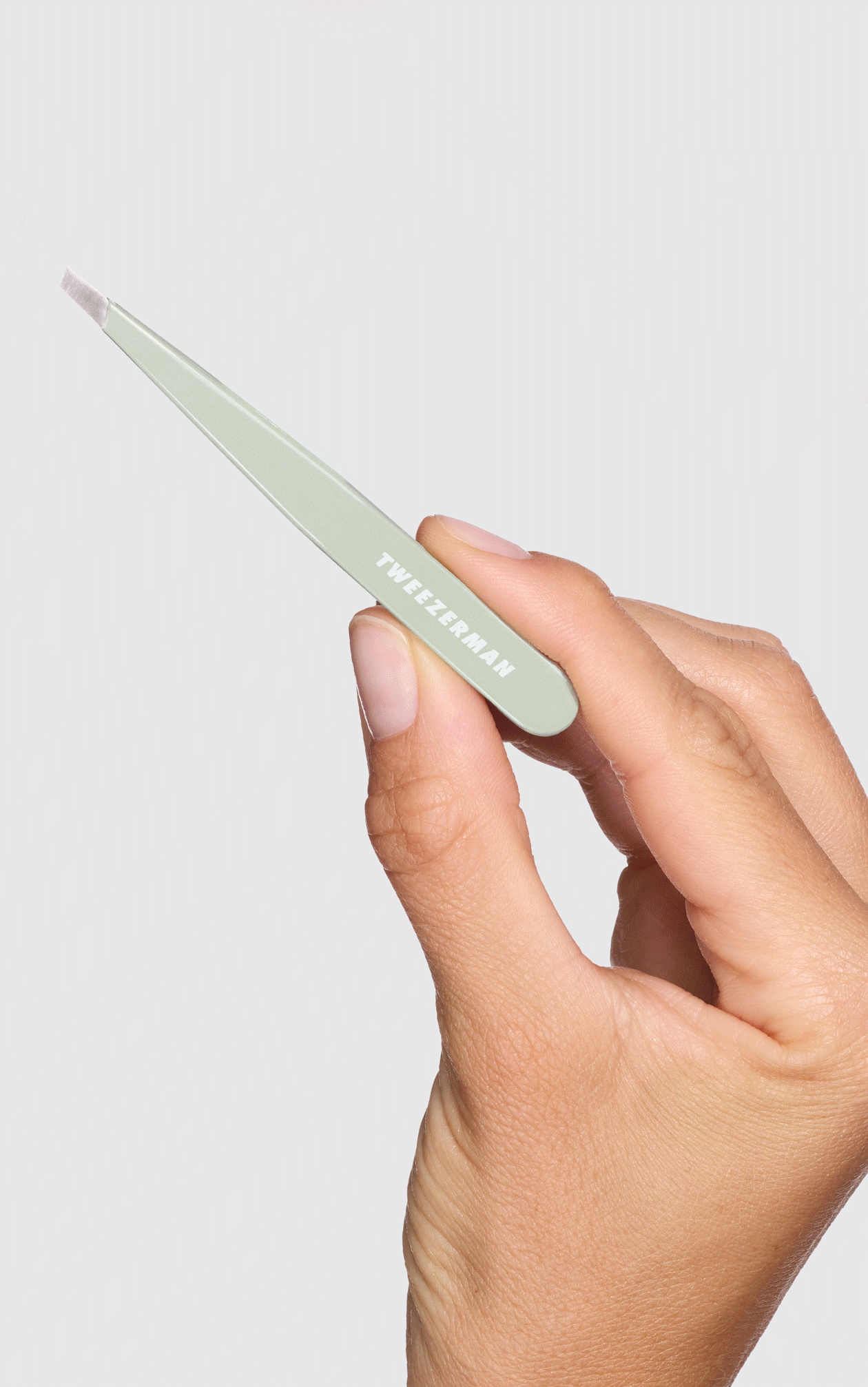 Model holding Pistachio Slant Tweezer, Rose god brow scissors, and pink neon brow set