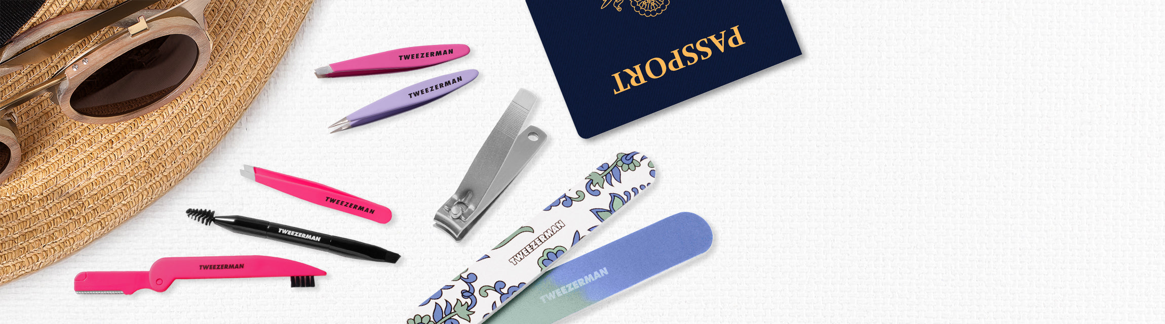 Set of grooming tools including Mini Brow Rescue Kit, Paisely Manicure Kit
, Mini Oval Slant and Point
, Brow & Facial Grooming Set
 on a white surface with a passport in the background.