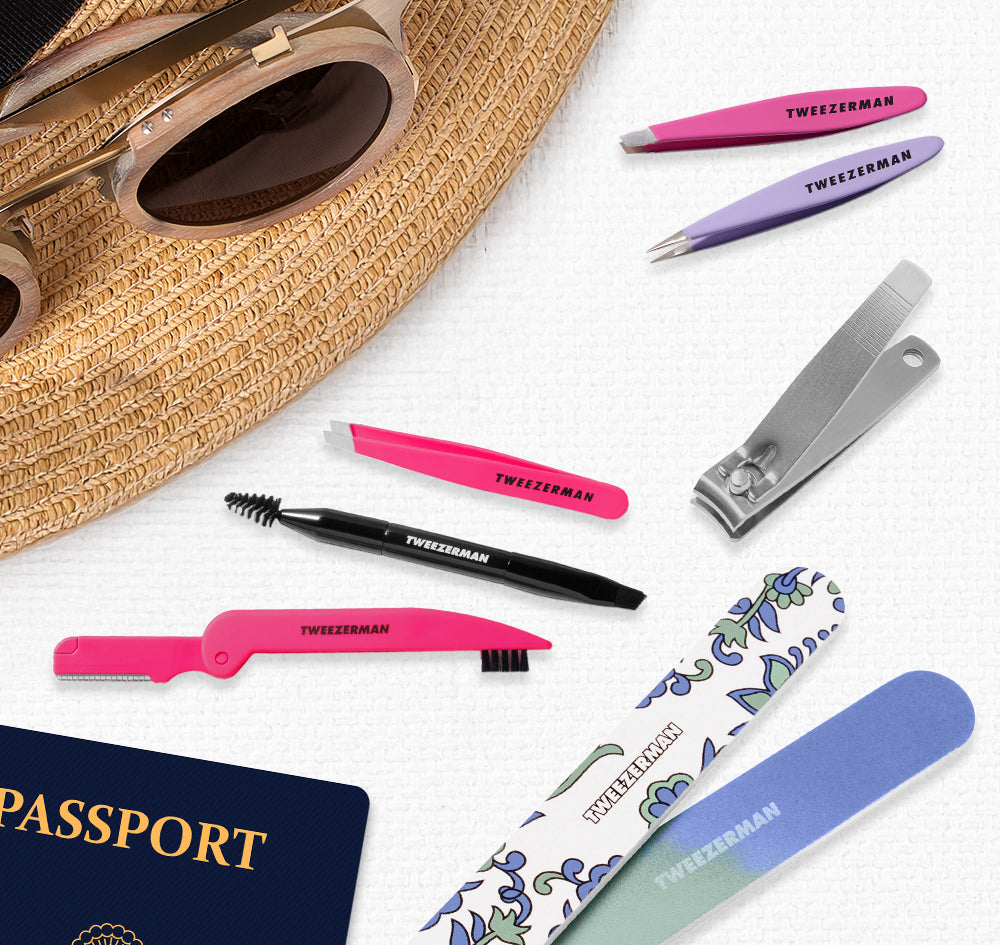 Set of grooming tools including Mini Brow Rescue Kit, Paisely Manicure Kit
, Mini Oval Slant and Point
, Brow & Facial Grooming Set
 on a white surface with a passport in the background.