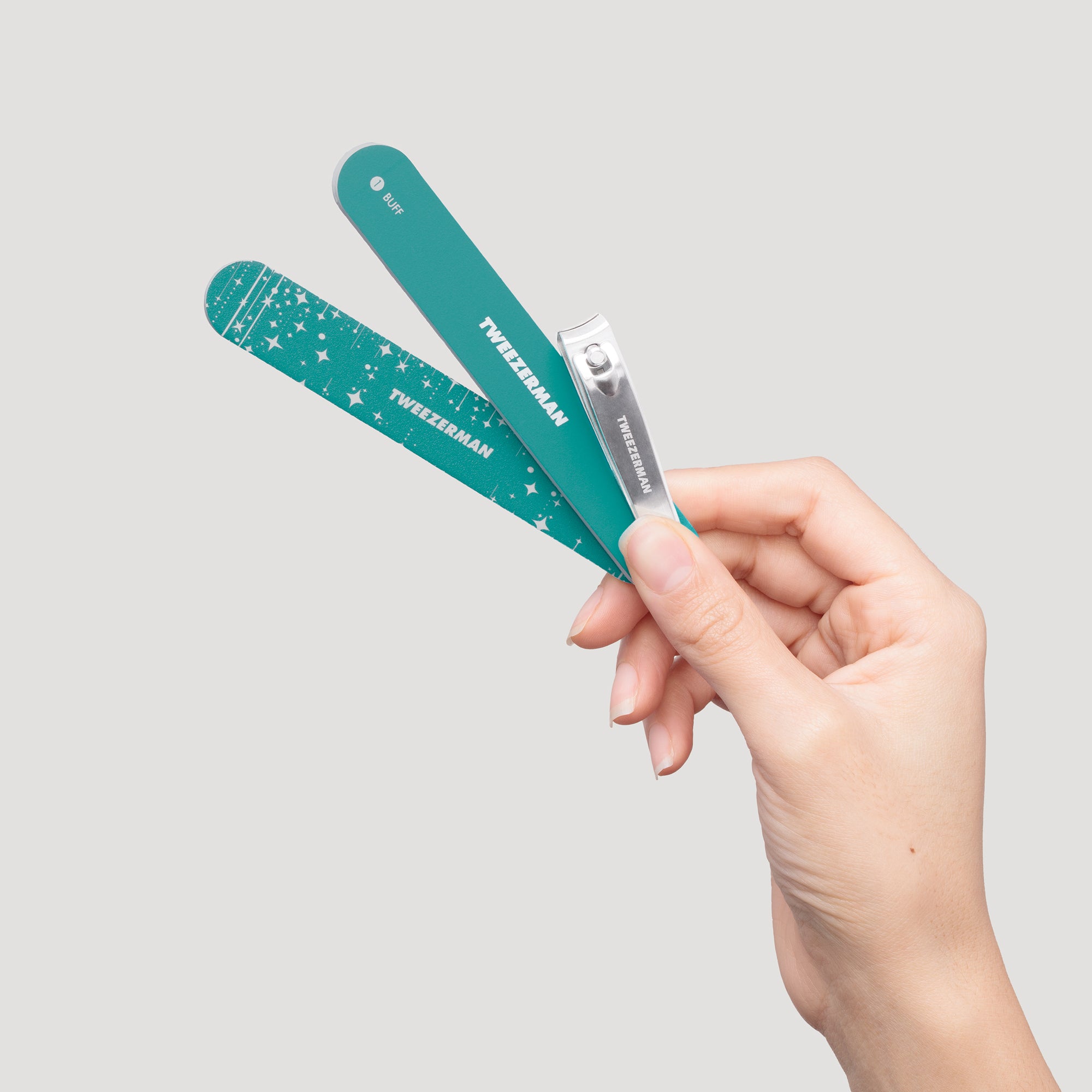 Model holding turquoise nail file, buffer, and nail clipper