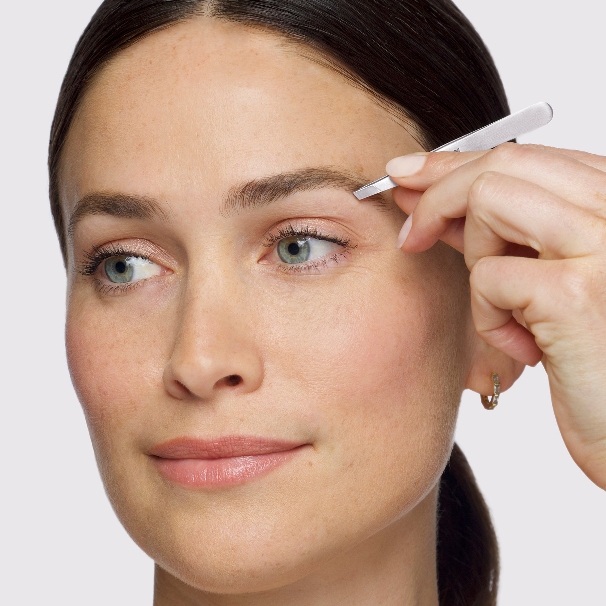 Model using Brow &amp; Facial Grooming Set&#39;s Slant Tweezer,