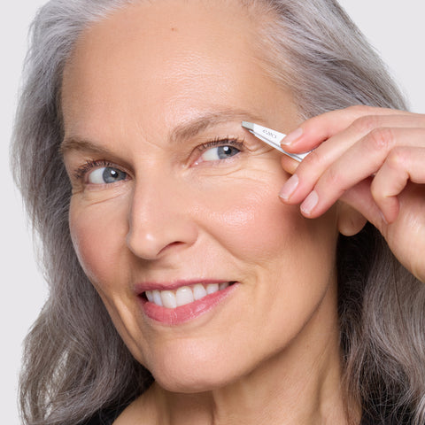 Model holding and using The Devil Wears Prada 2 Mini Slant Tweezer