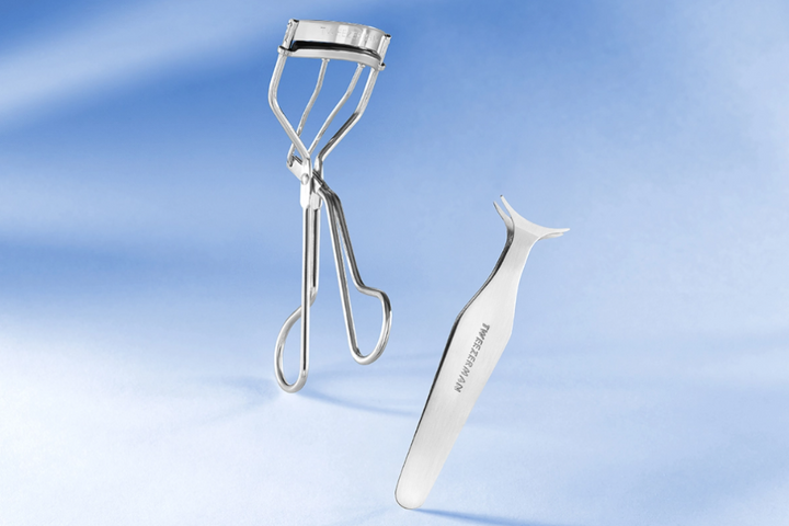 Eyelash curler and lash applicator tool on a blue gradient background