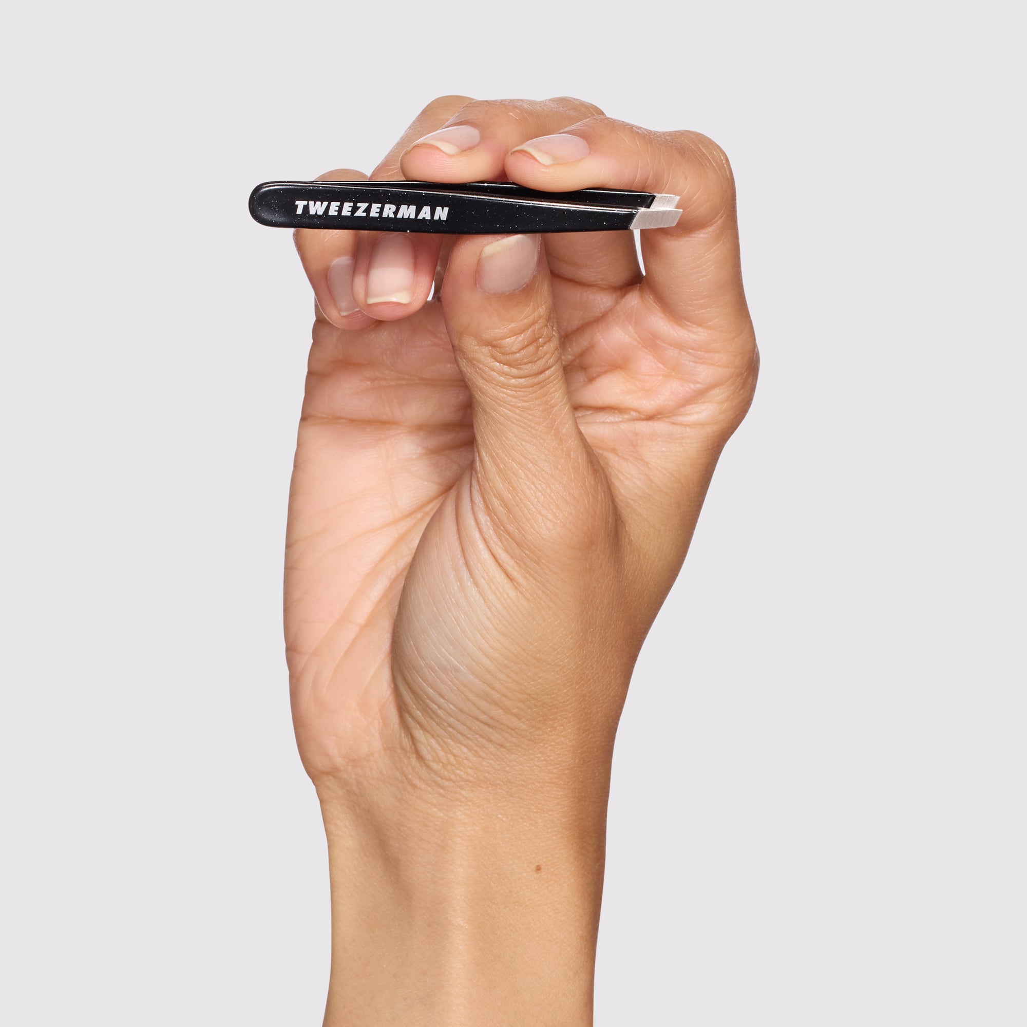 Close-up shot of Model holding Dusted Onyx Mini Slant Tweezer
