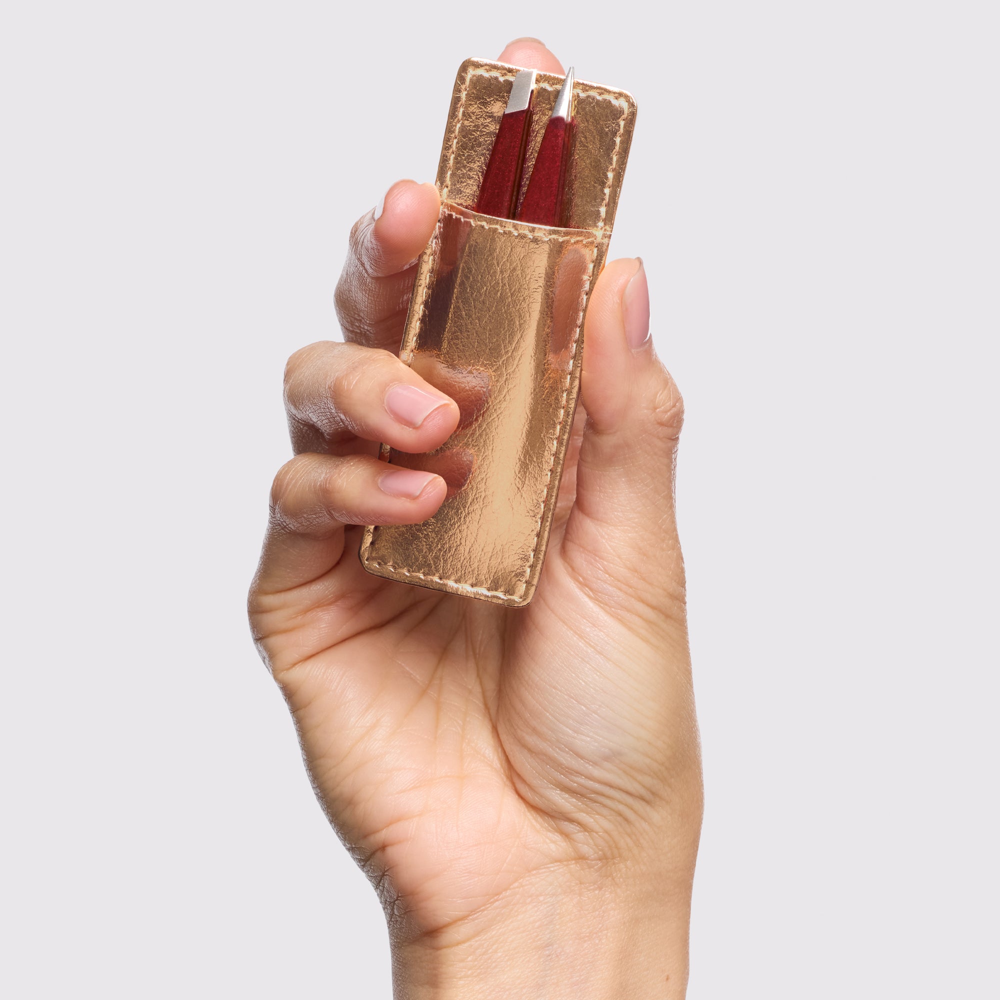 Model holding Vintage Rose Mini Tweezer Set in gold-colored case