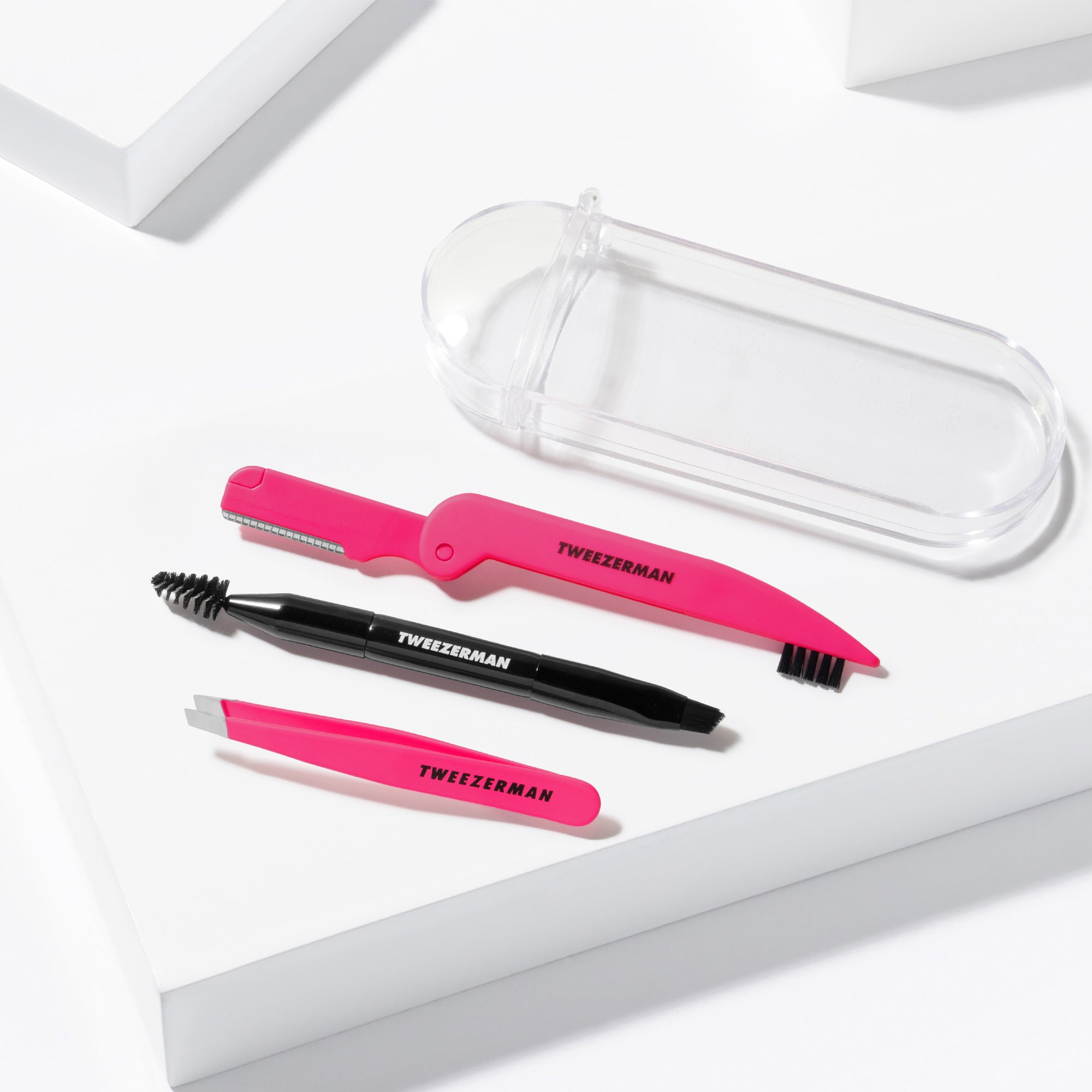 Mini Brow Rescue Kit including Mini Pink Slant Tweezer, Mini Angled Brow Brush and Pink Dual-sided Precision Folding Razor and a clear case placed on a white background