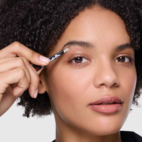 Model holding and using The Devil Wears Prada 2 Slant Tweezer