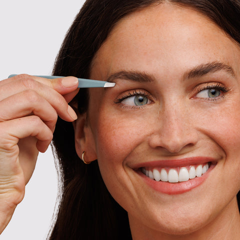 Female Model using the Mist Blue Slant Tweezer to tweeze brows