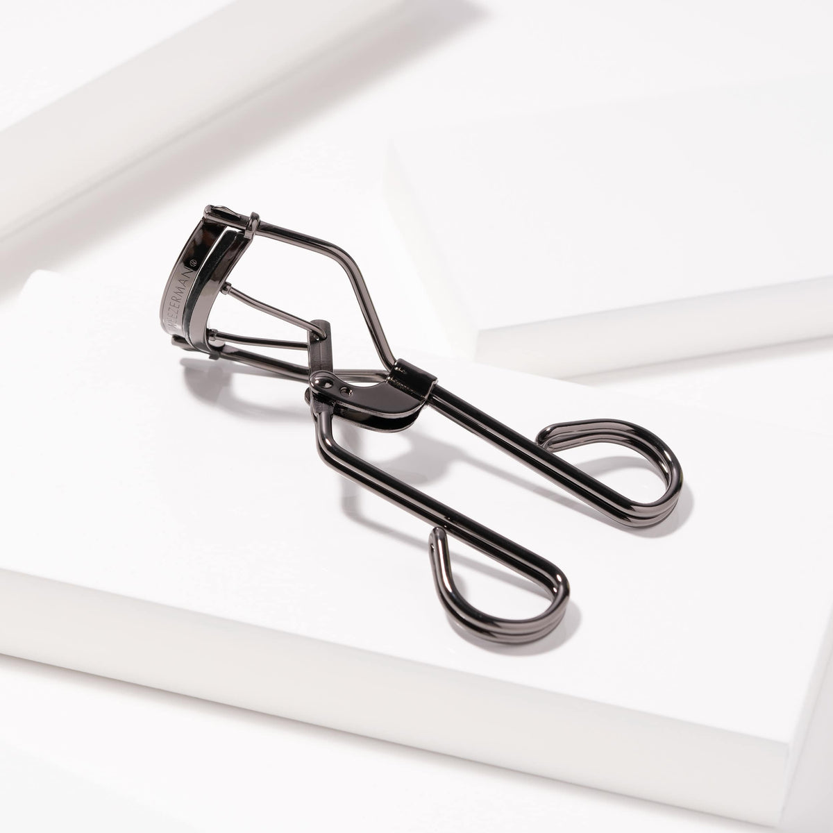 Tweezerman Pro Master Lash Curler resting on a white display surface