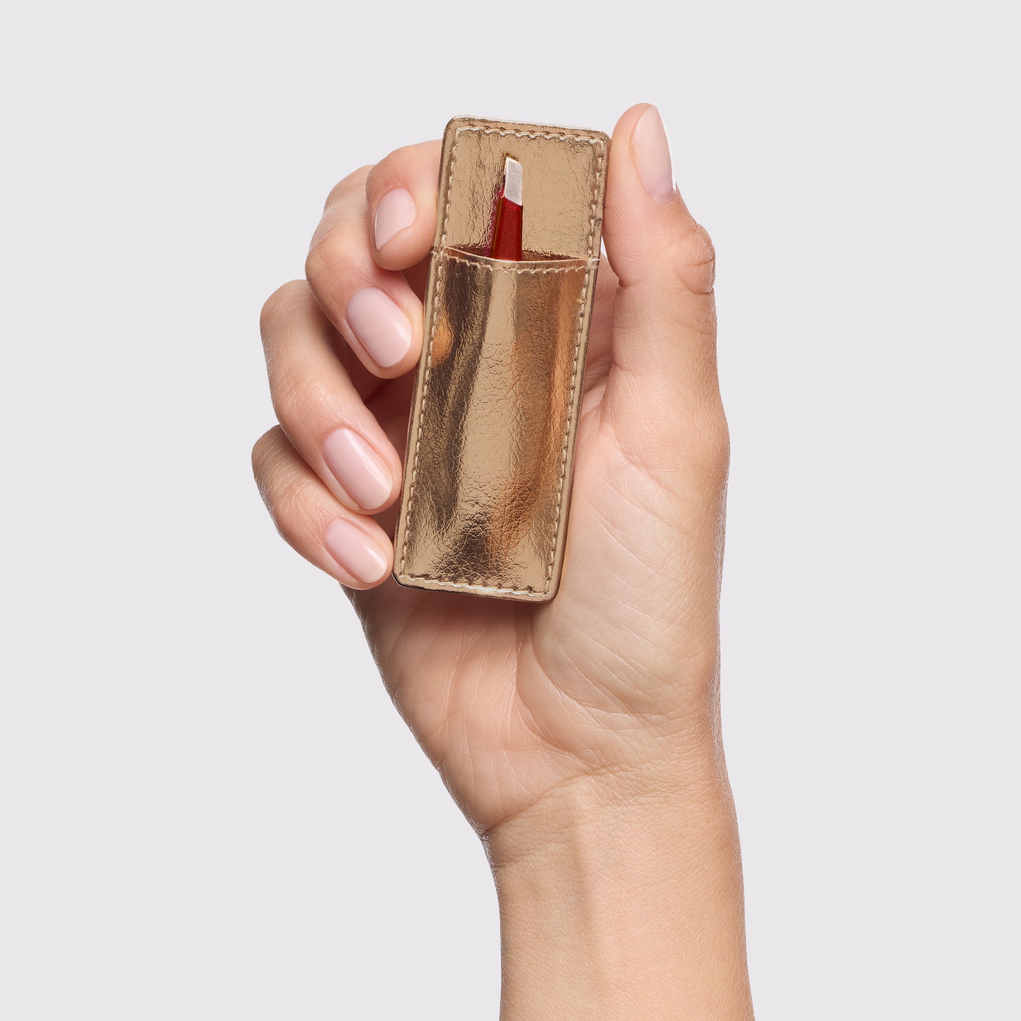 Model holding gold-colored tweezer case