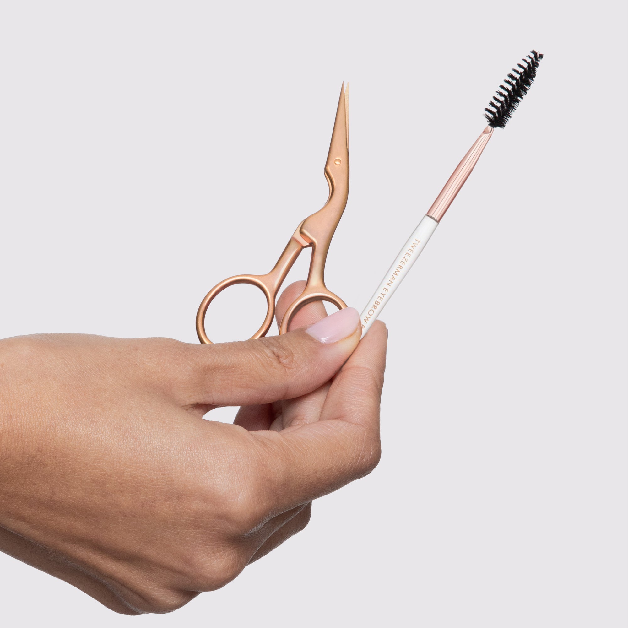 Model holding Rose Gold Brow Shaping Scissors and Brush