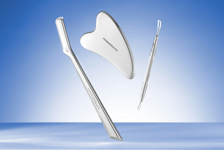 Set of skincare tools including a facial razor, gua sha, and skincare tool on a blue gradient background