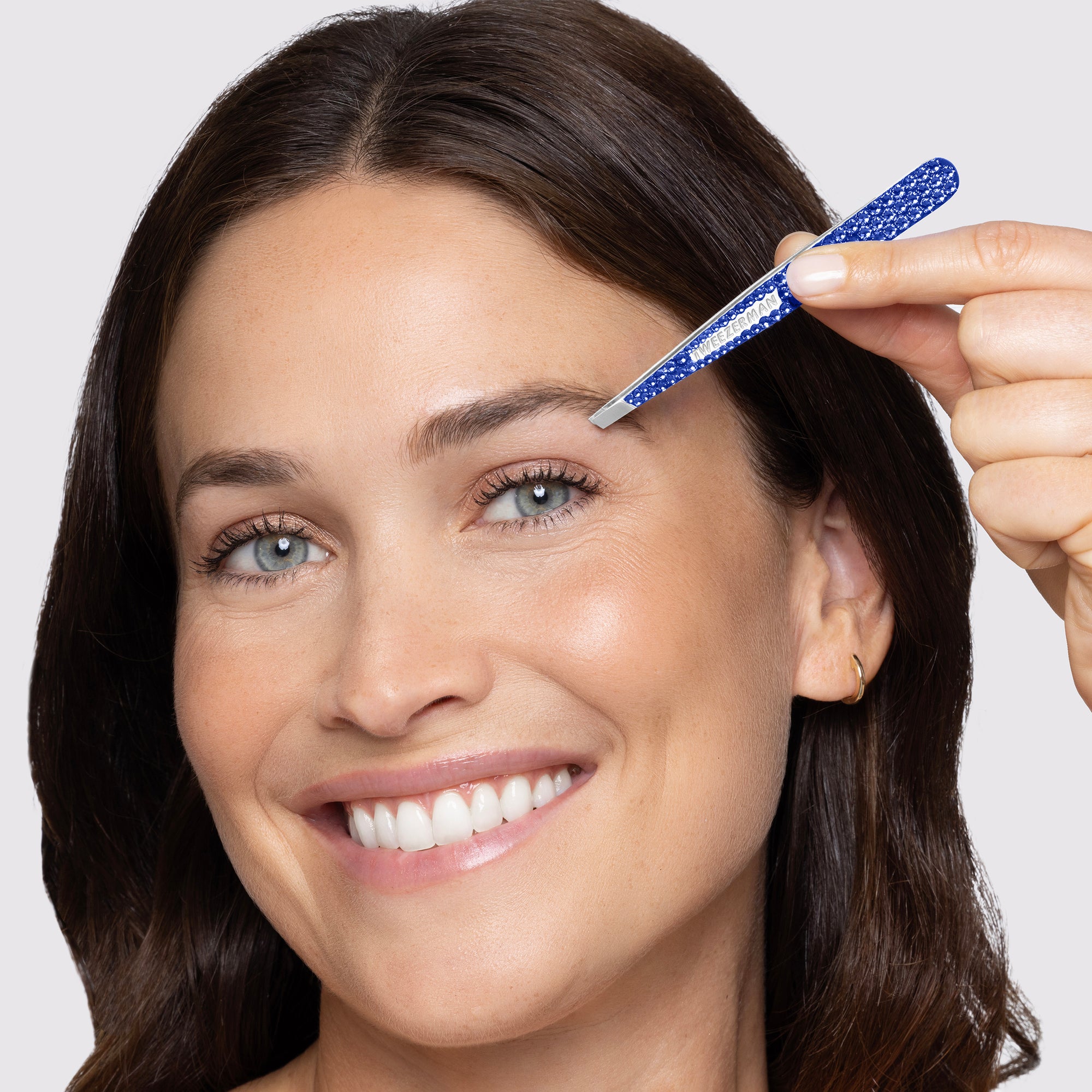 Model using Tweezerman special edition Blue Sapphire Swarovski Crystal Slant Tweezer.