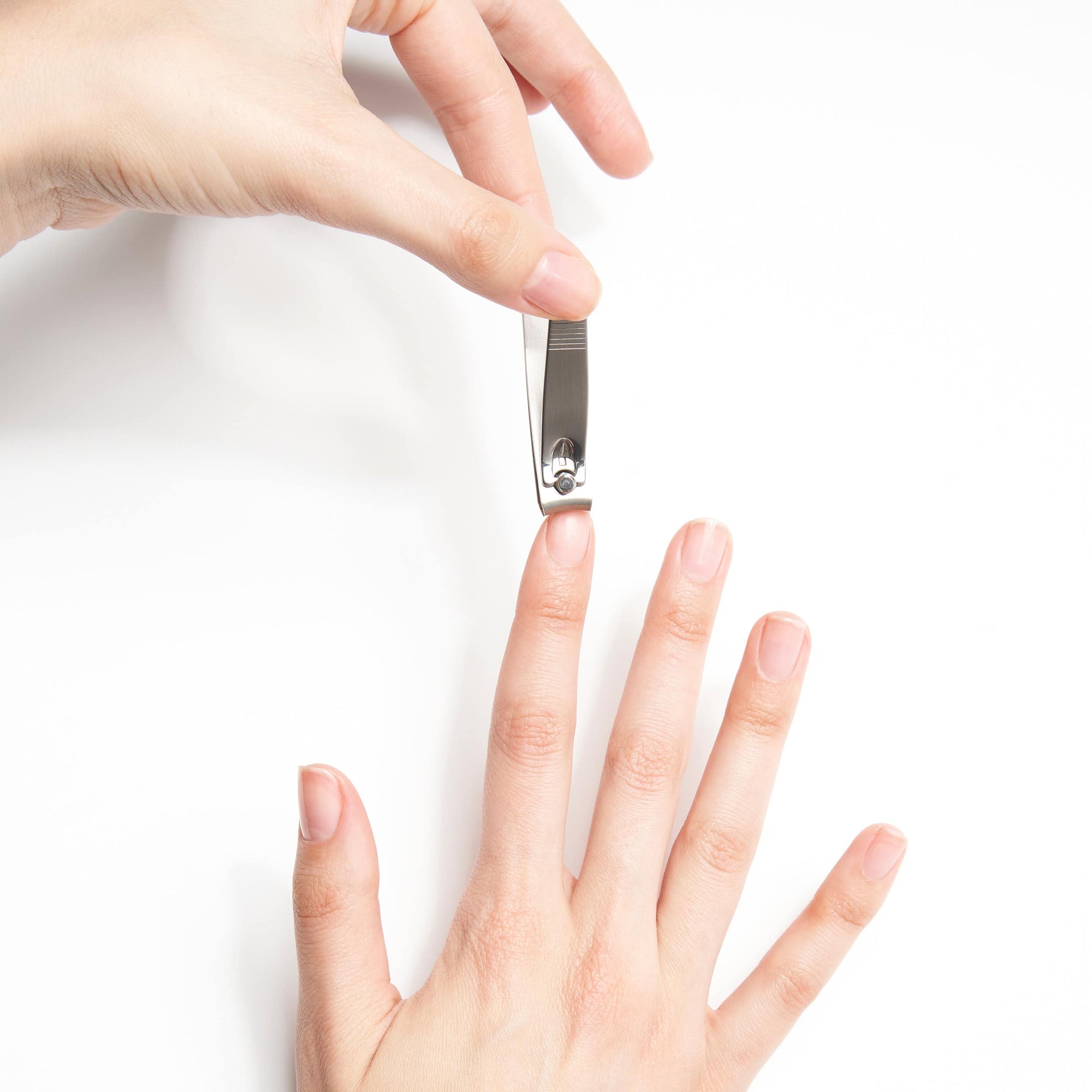 Model holding fingernail clipper pushing down on lever to cut fingernail