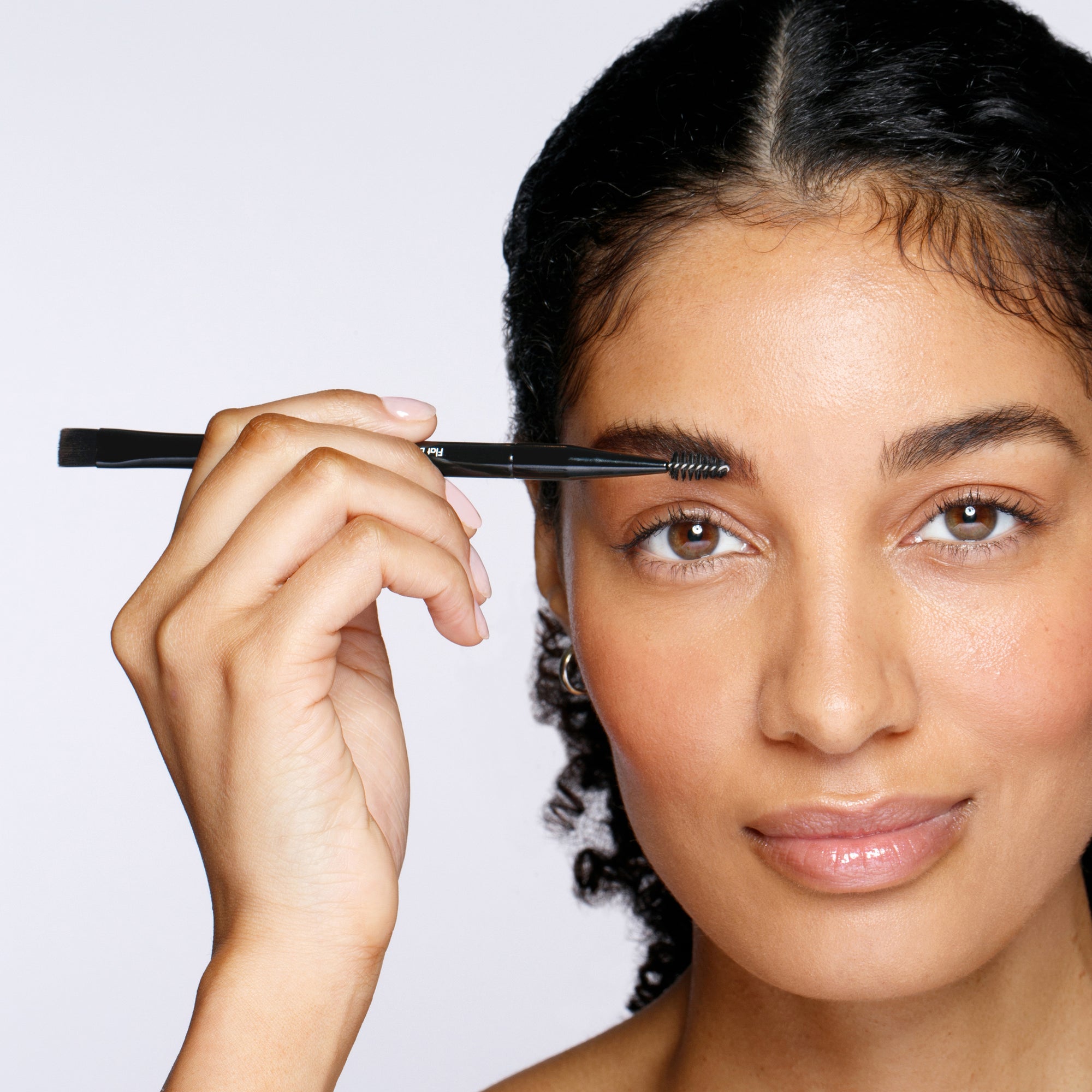 Model using Spoolie end of Dual Ended Flat brow brush and spoolie